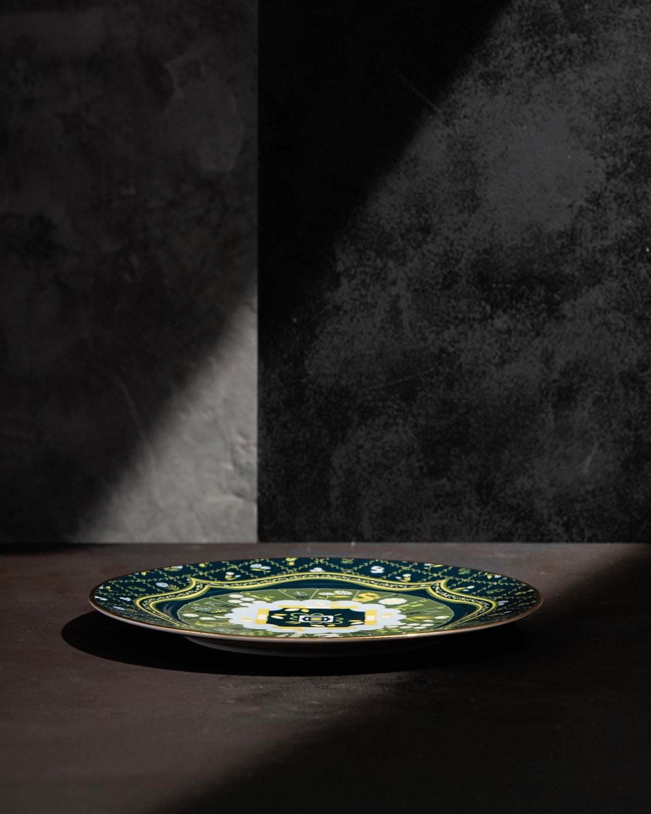 Teal ceramic decorative plate with green and white floral medallion pattern and ornamental border
