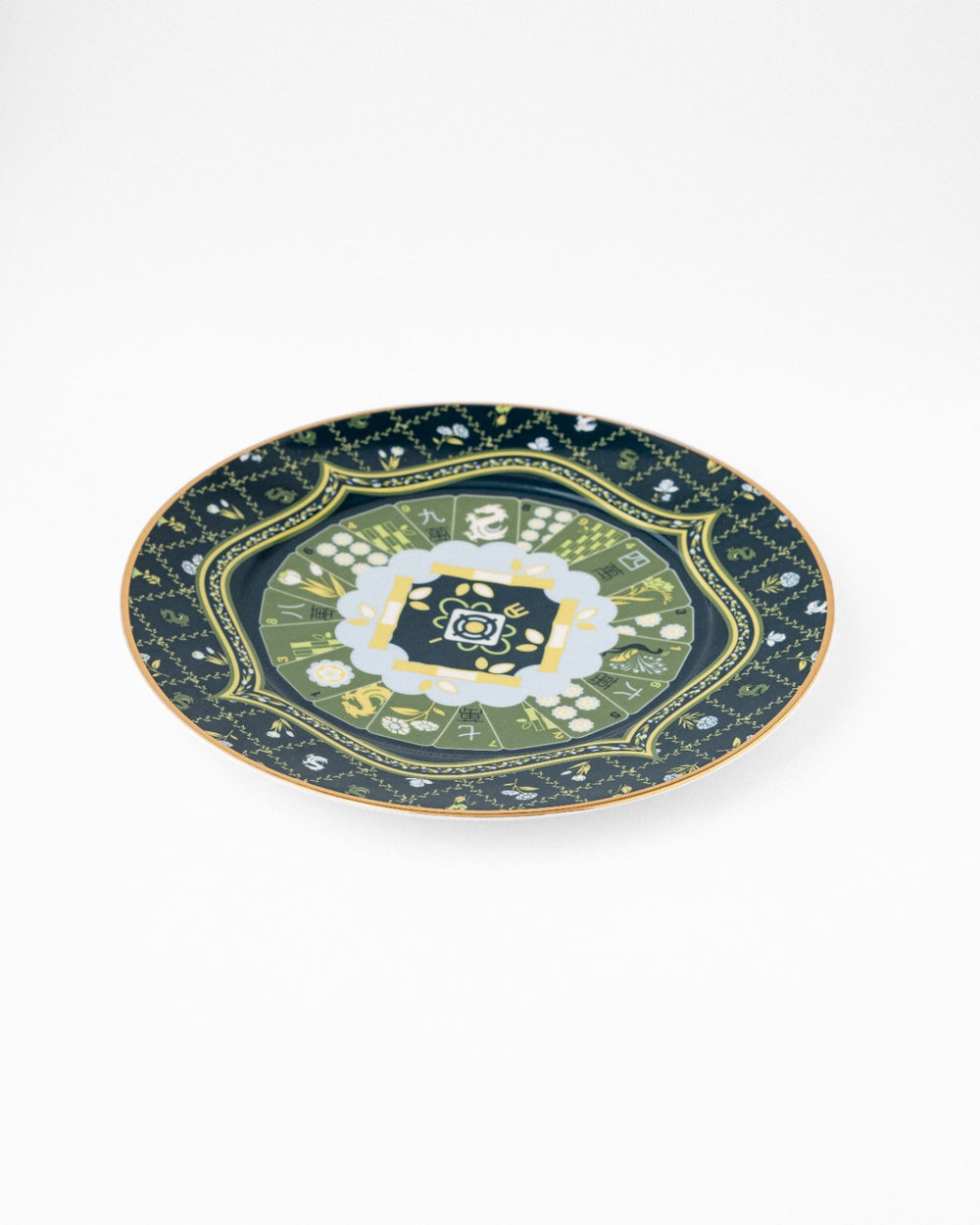 Navy ceramic serving plate with gold trim and ornate green floral central medallion, photographed at angle on white background