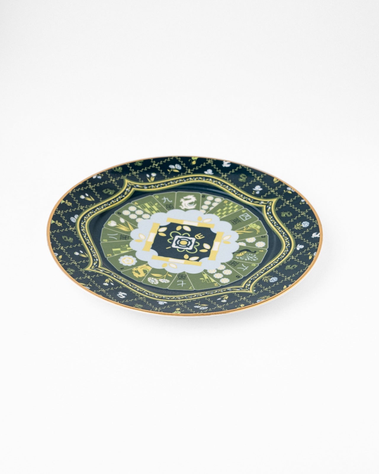 Navy ceramic serving plate with gold trim and ornate green floral central medallion, photographed at angle on white background