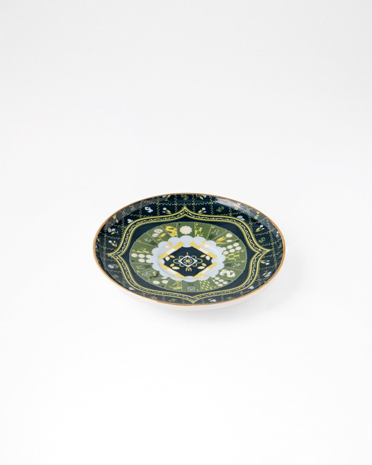 Navy ceramic saucer with gold border and green floral center design on white background