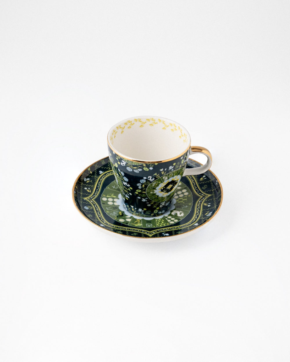 Navy teacup and matching saucer with green floral pattern, beige handle, cream interior on white background